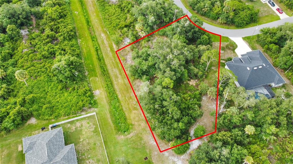 An aerial view shows a wooded, irregularly shaped vacant lot outlined in red — ANCIENT ROAD, NORTH PORT, FL