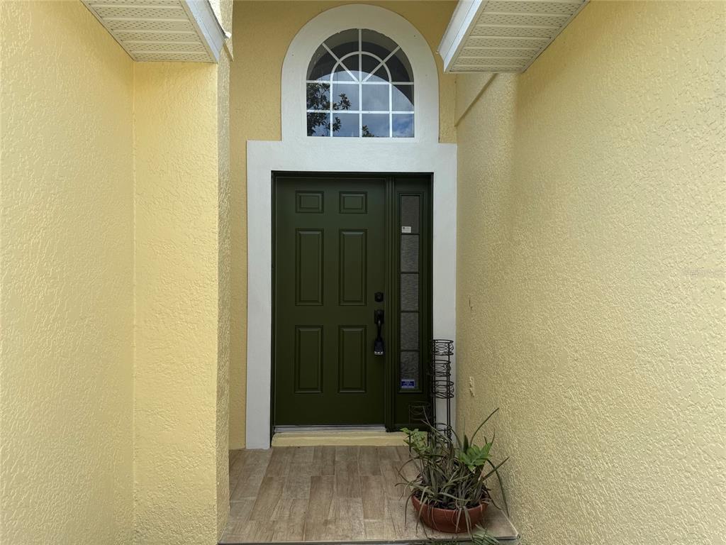 A dark green front door with a side light and arched transom window under a porch — 1221 SINGLETON CIRCLE, GROVELAND, FL