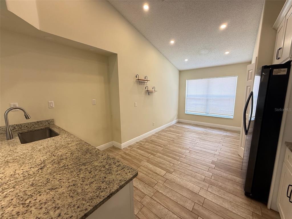 A kitchen with granite countertops, a stainless steel sink, and wood-look tile flooring — 1221 SINGLETON CIRCLE, GROVELAND, FL