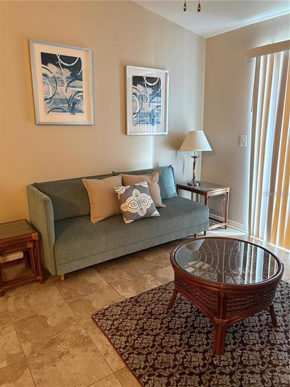 A living room features a teal sofa, two framed prints, and a round rattan coffee table — 2516 GRASSY POINT DRIVE UNIT 200, LAKE MARY, FL