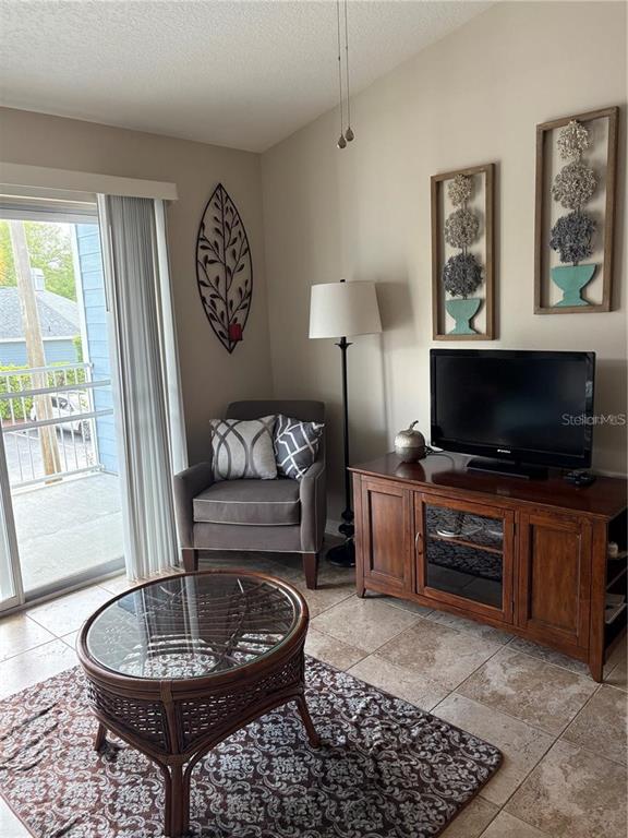 A living room features a glass-topped wicker coffee table, a gray armchair, and a television — 2516 GRASSY POINT DRIVE UNIT 200, LAKE MARY, FL