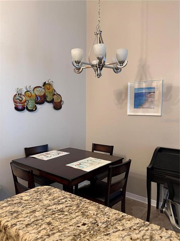 A dining area features a dark wood square table, four chairs, and a metal chandelier — 2516 GRASSY POINT DRIVE UNIT 200, LAKE MARY, FL