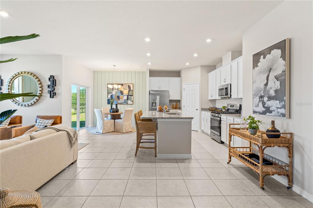 An open-concept kitchen and dining area features white cabinetry, a central island, and tile flooring — 3712 ROLLING RIDGE BEND, DAVENPORT, FL