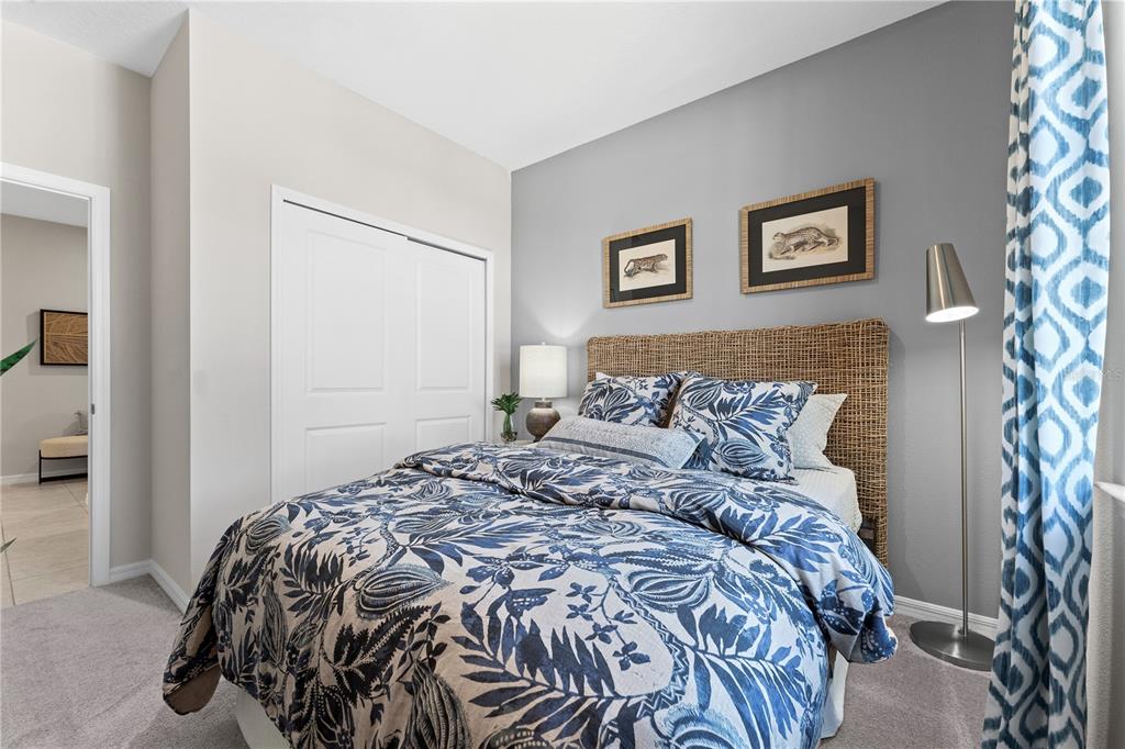 A bedroom features a bed with a woven headboard, blue patterned bedding, and gray walls — 3712 ROLLING RIDGE BEND, DAVENPORT, FL