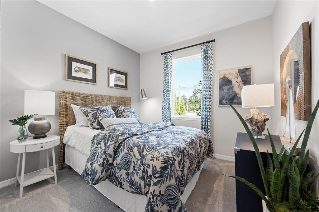 A bedroom features a bed with a woven headboard, blue patterned bedding, and a side table — 3712 ROLLING RIDGE BEND, DAVENPORT, FL