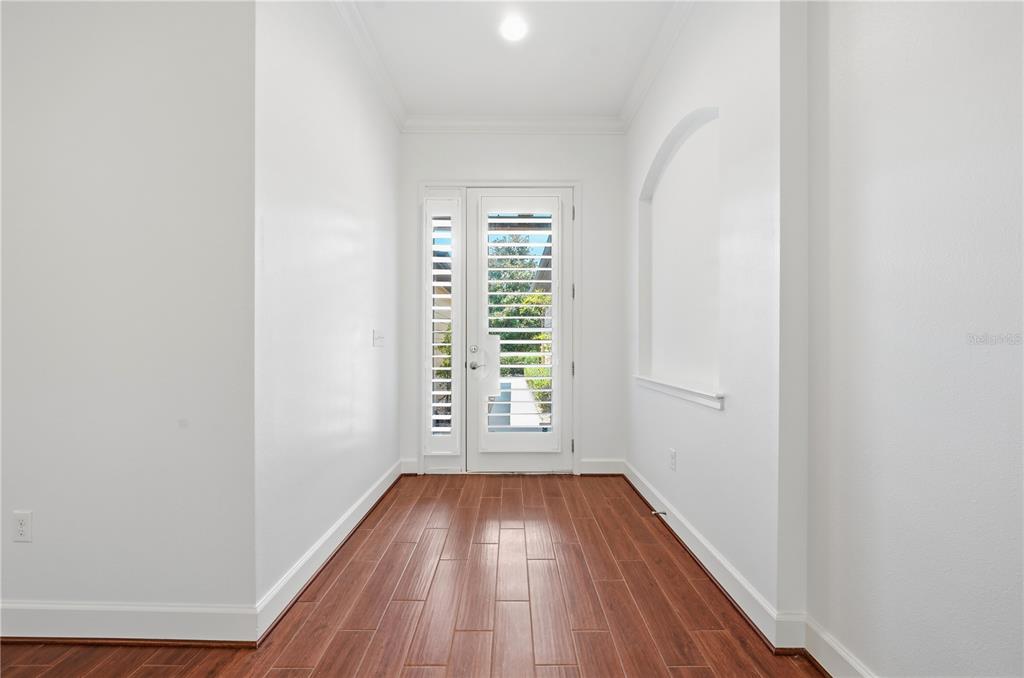 A bright entryway features white walls, wood-look tile flooring, and a glass-paneled front door — 1031 KILKENNY LANE, ORMOND BEACH, FL