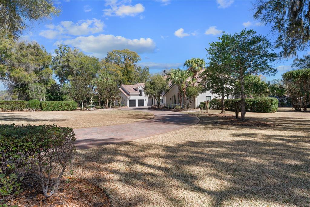 A paved driveway leads to a large house with a multi-car garage and landscaping — 3409 SE 17TH COURT, OCALA, FL
