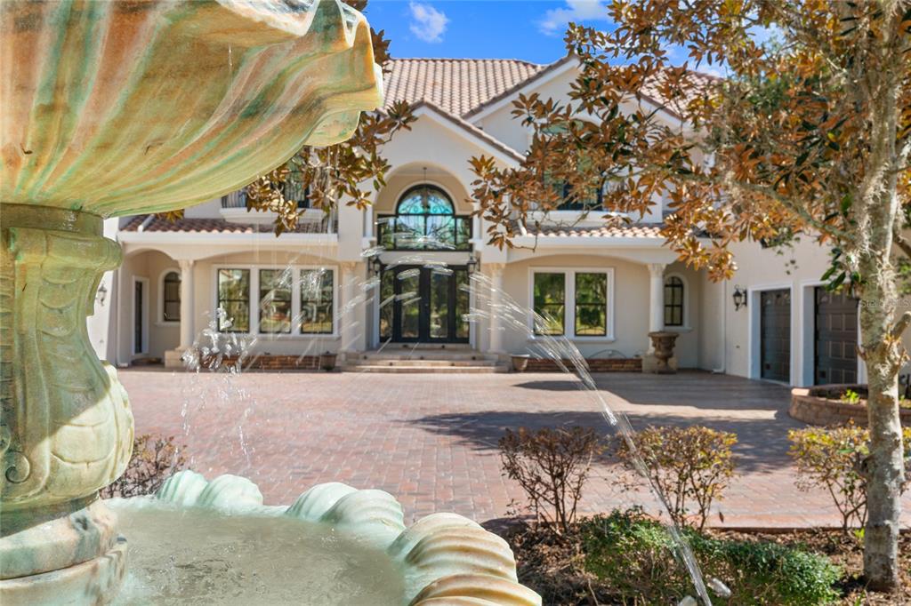 A large two-story house with a paved driveway and a foreground water fountain — 3409 SE 17TH COURT, OCALA, FL