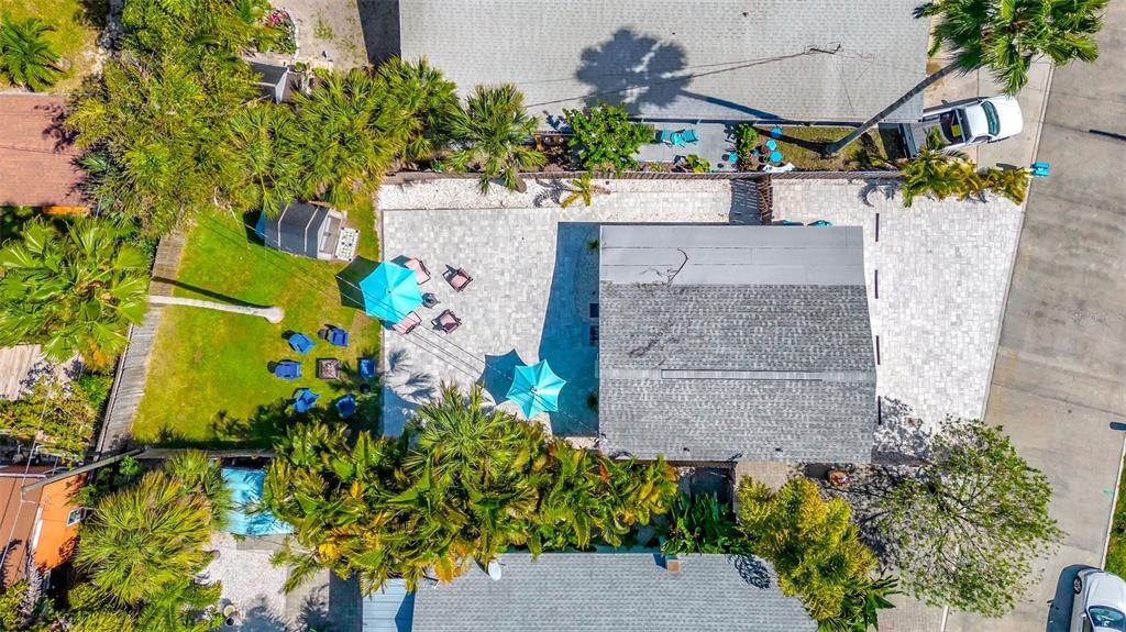 An aerial view shows a house with a paved patio, umbrellas, and a grassy yard — 13121 4TH STREET E UNIT 2, MADEIRA BEACH, FL