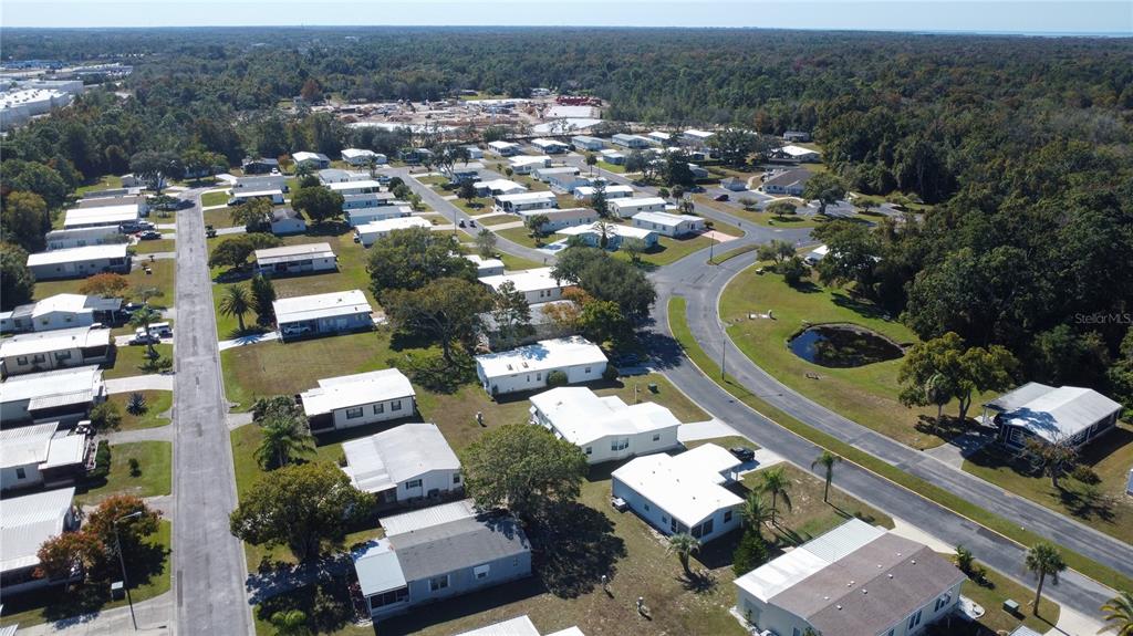 An aerial view shows a residential neighborhood with many white mobile homes and paved streets — FOREST GLENN DRIVE, SPRING HILL, FL