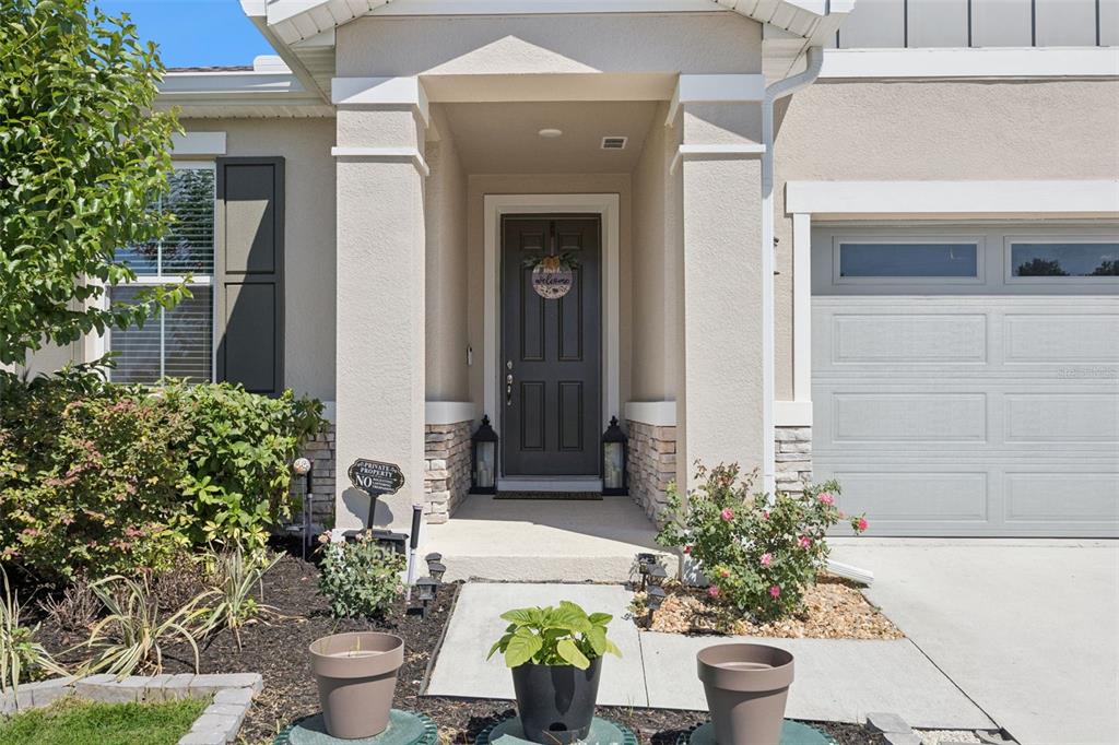 The exterior of a house features a covered entryway with a dark door and garage — 10053 SPRING LAKE DRIVE, CLERMONT, FL