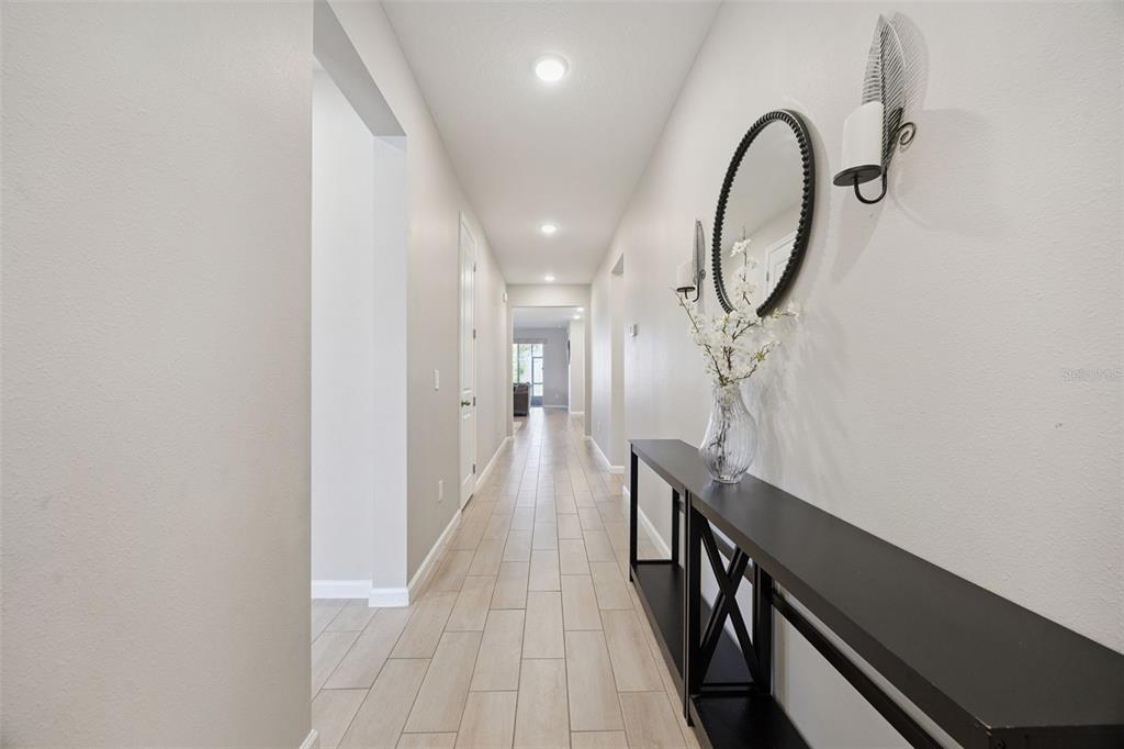 A long hallway with light-colored tile flooring leads toward an open living area — 10053 SPRING LAKE DRIVE, CLERMONT, FL