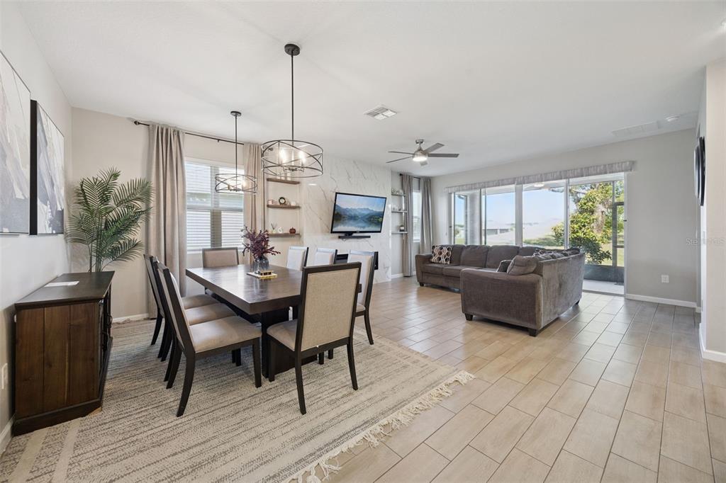 An open-concept dining and living area features tile flooring, a marble-look fireplace, and sliding doors — 10053 SPRING LAKE DRIVE, CLERMONT, FL