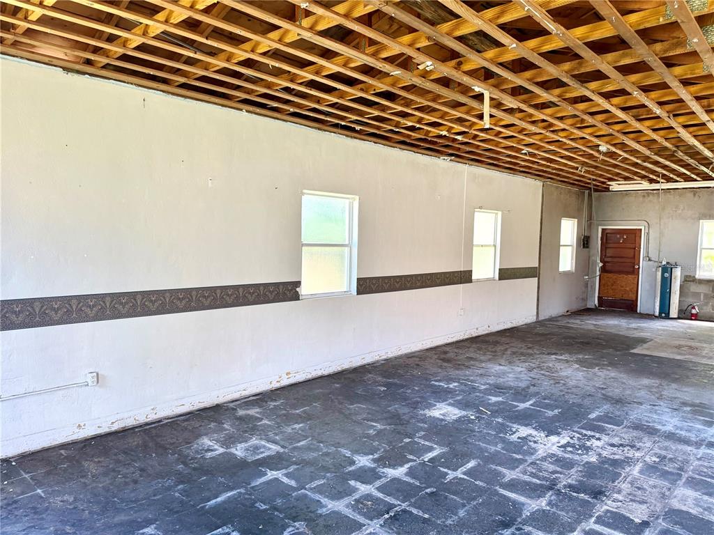 An unfinished room with exposed ceiling joists, white walls, and a dark tiled floor — 844 KLONDIKE STREET, WINTER GARDEN, FL
