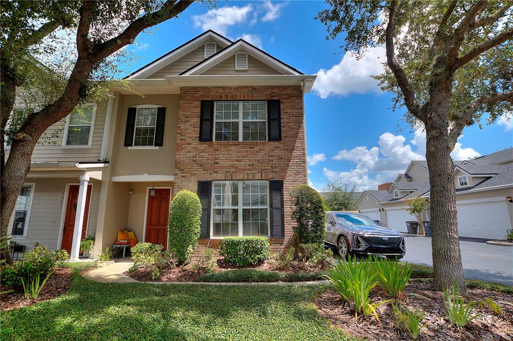 A two-story townhouse features a brick facade, black shutters, and a front entrance with landscaping — 1259 INDIANA AVENUE, WINTER PARK, FL