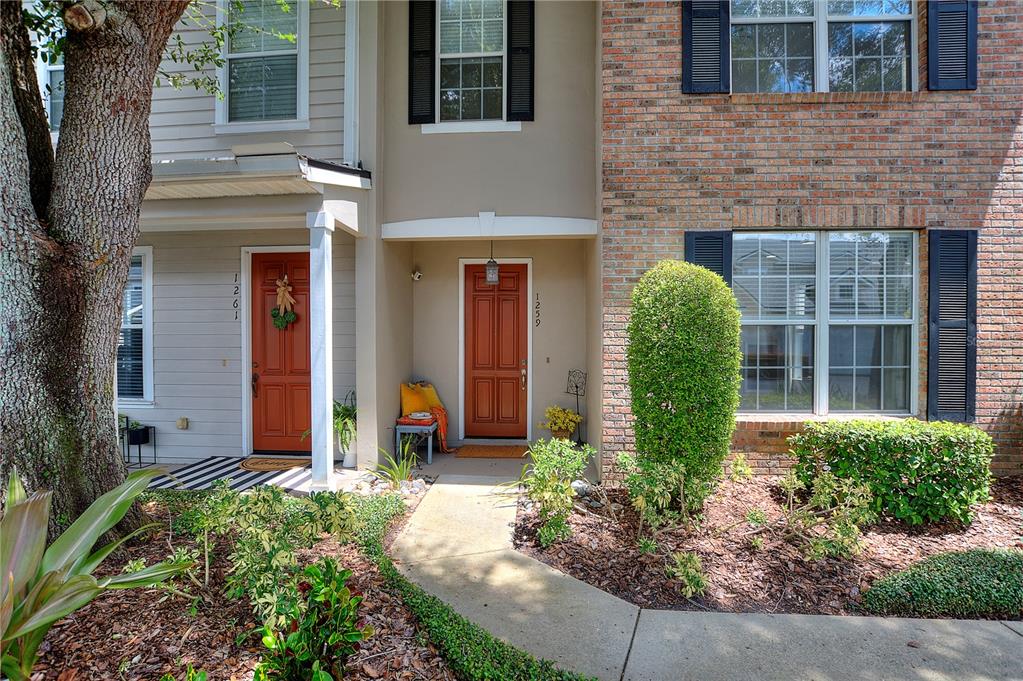 The exterior of two adjacent townhomes features brick and siding facades with orange front doors — 1259 INDIANA AVENUE, WINTER PARK, FL