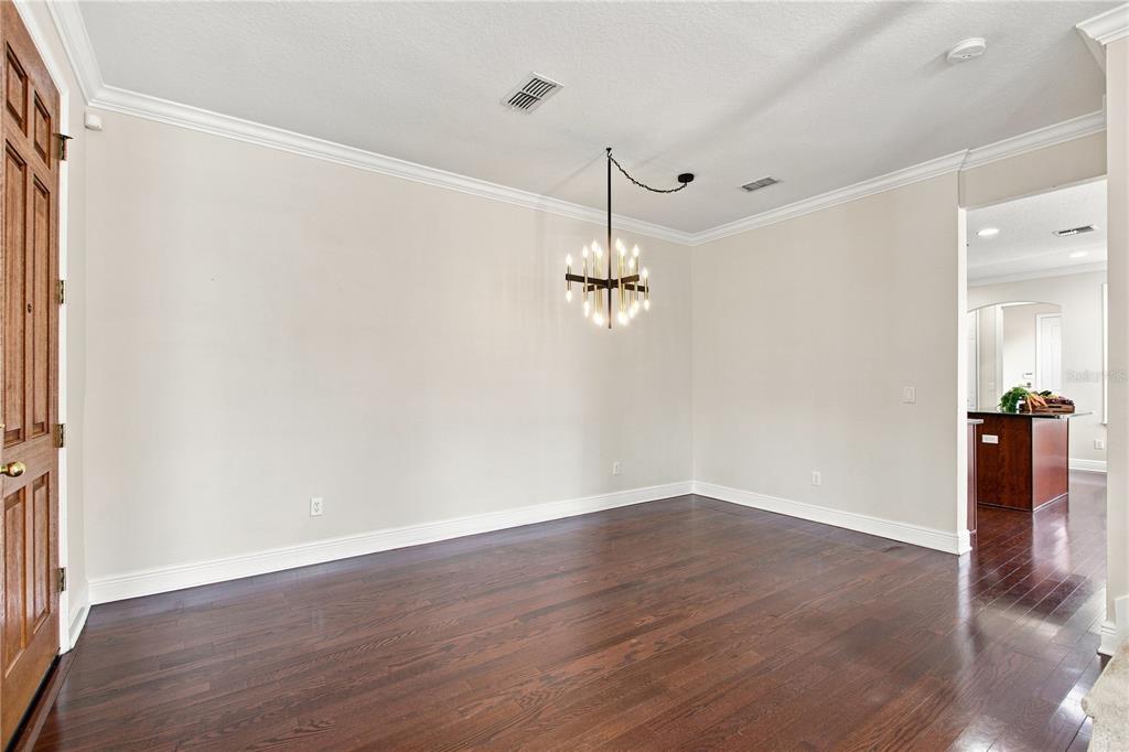 A dining room with dark hardwood floors, crown molding, and a modern tiered chandelier — 1259 INDIANA AVENUE, WINTER PARK, FL