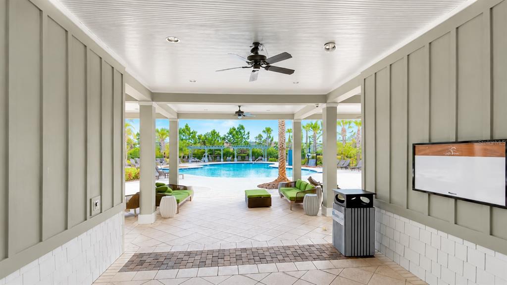 A covered outdoor patio with ceiling fans overlooks a swimming pool and lounge area — 1652 HUBBELL ROAD, WESLEY CHAPEL, FL