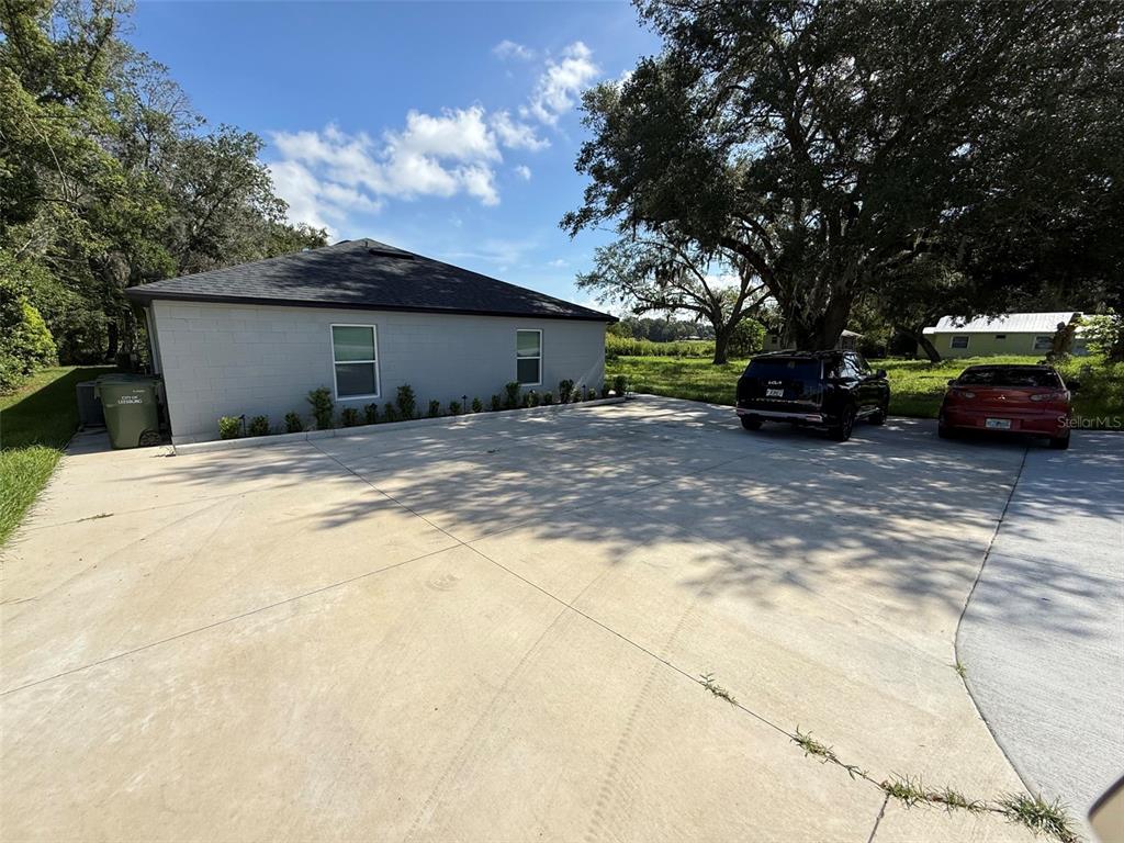 A gray concrete block house features a large concrete driveway with two parked cars — 2108 SOUTH STREET, LEESBURG, FL