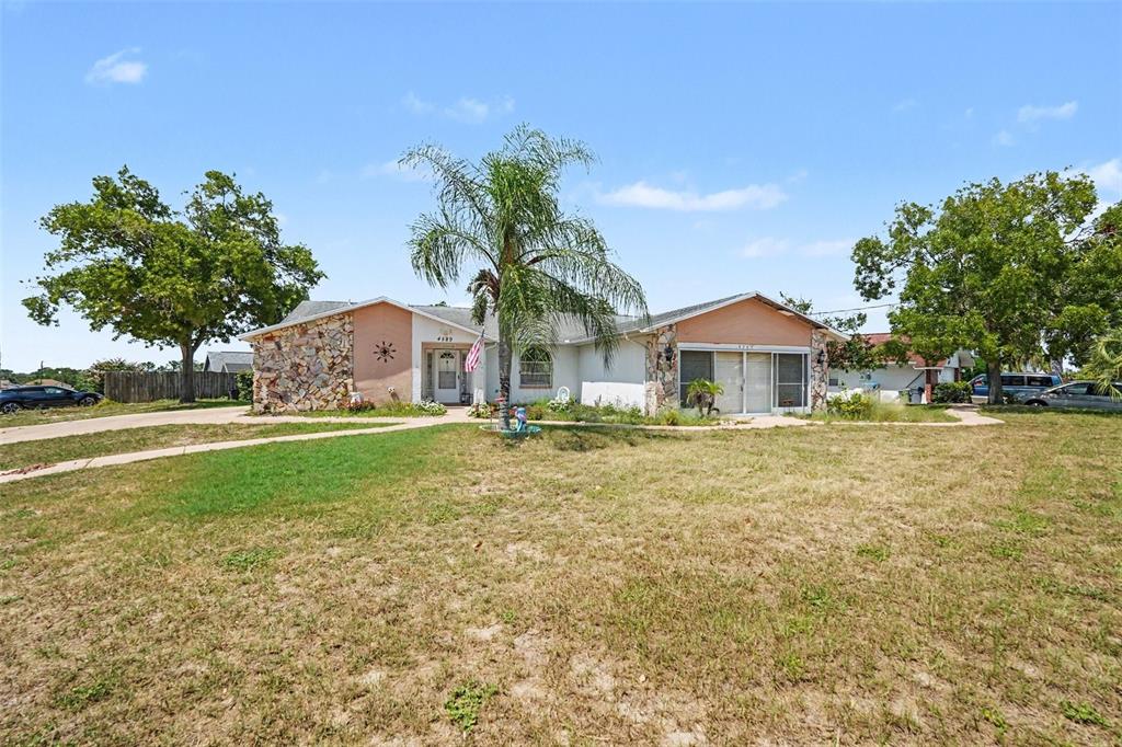 A single-story house with a stone facade, a palm tree, and a large front yard — 4589 MARINER BLVD, SPRING HILL, FL