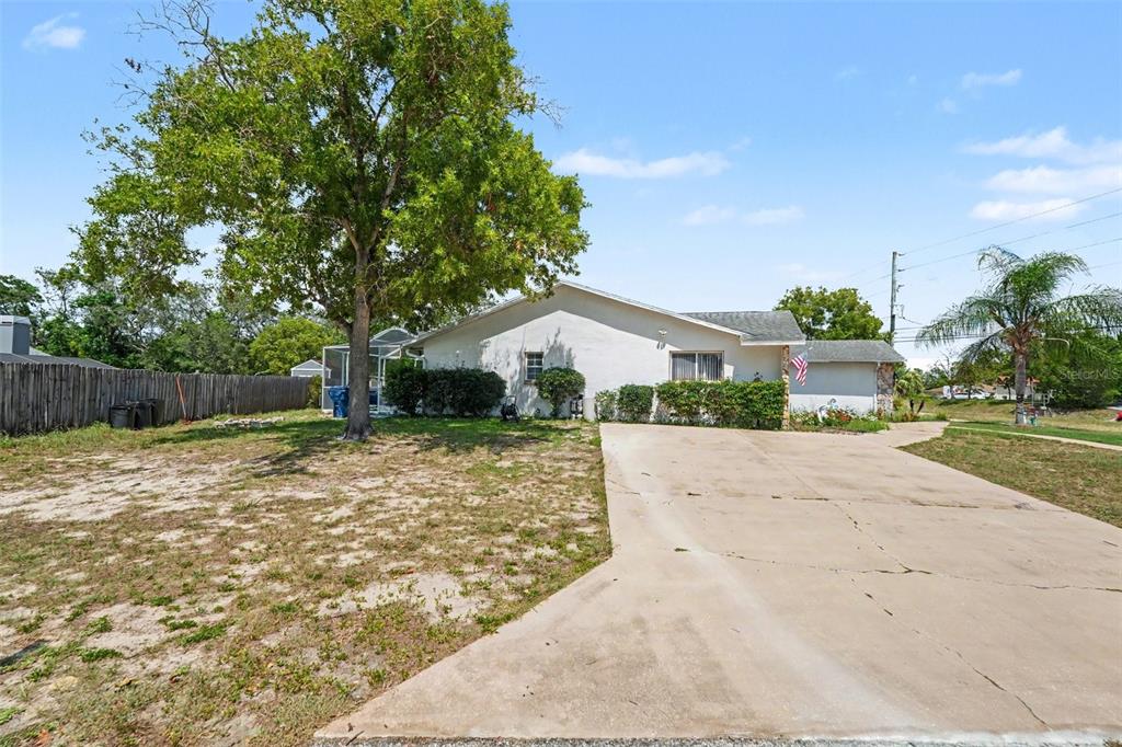 A single-story house with a concrete driveway, a large tree, and a wooden fence — 4589 MARINER BLVD, SPRING HILL, FL