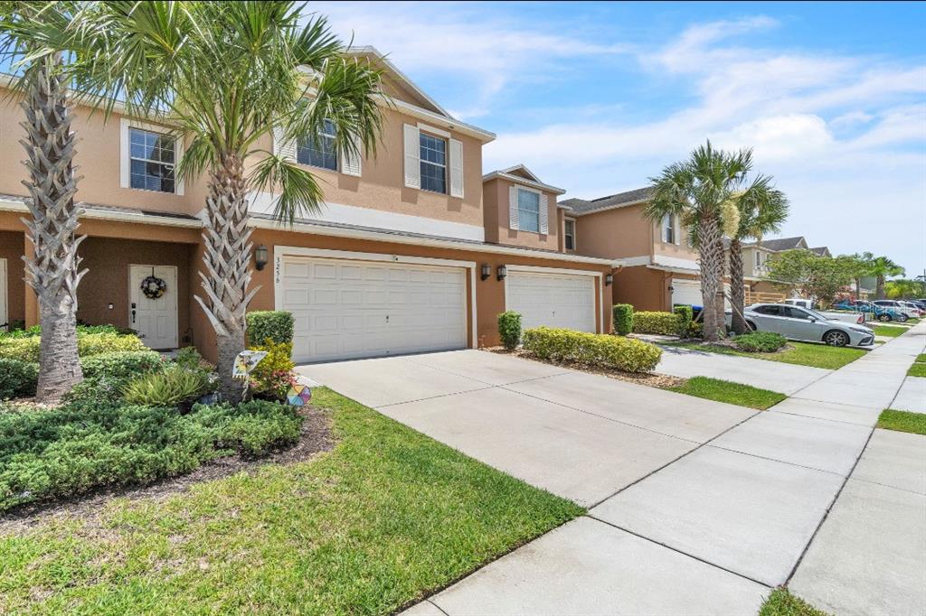 A two-story townhouse with a two-car garage, palm trees, and a concrete driveway — 3256 RODRICK CIRCLE, ORLANDO, FL