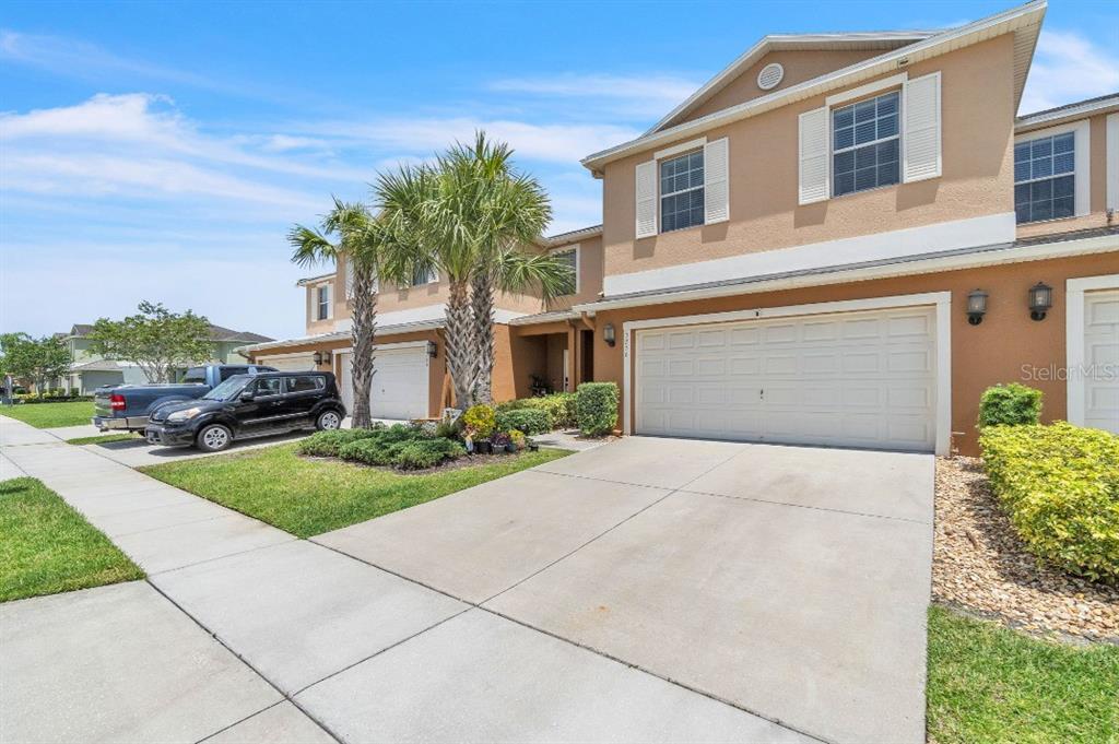 A two-story tan townhouse with a two-car garage and palm trees in the front yard — 3256 RODRICK CIRCLE, ORLANDO, FL