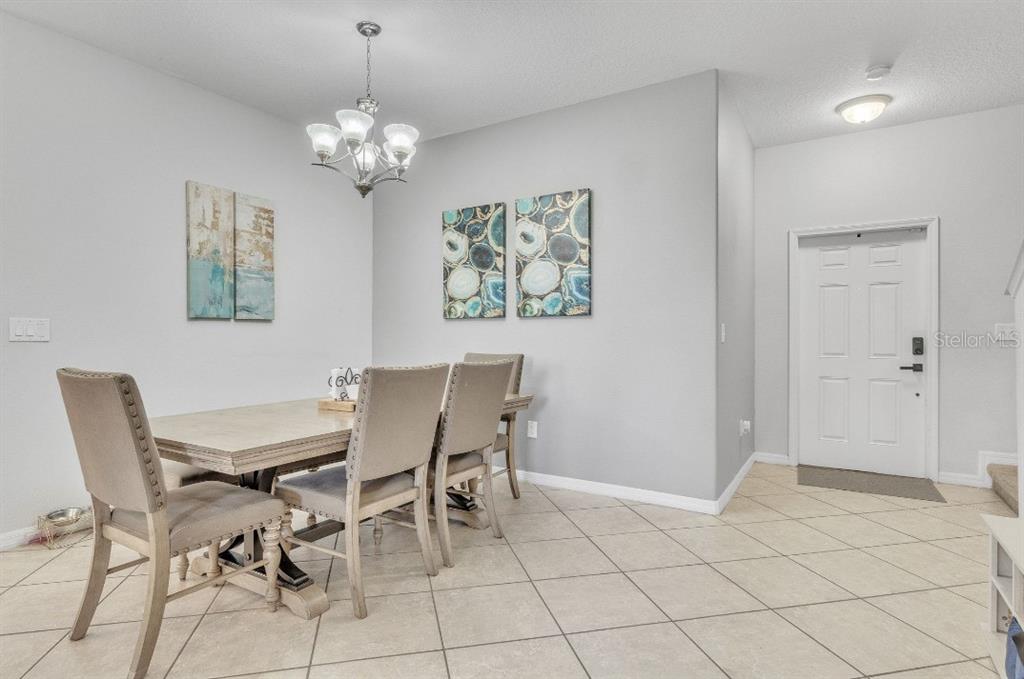 A dining room features a wooden table, upholstered chairs, a chandelier, and tiled flooring — 3256 RODRICK CIRCLE, ORLANDO, FL