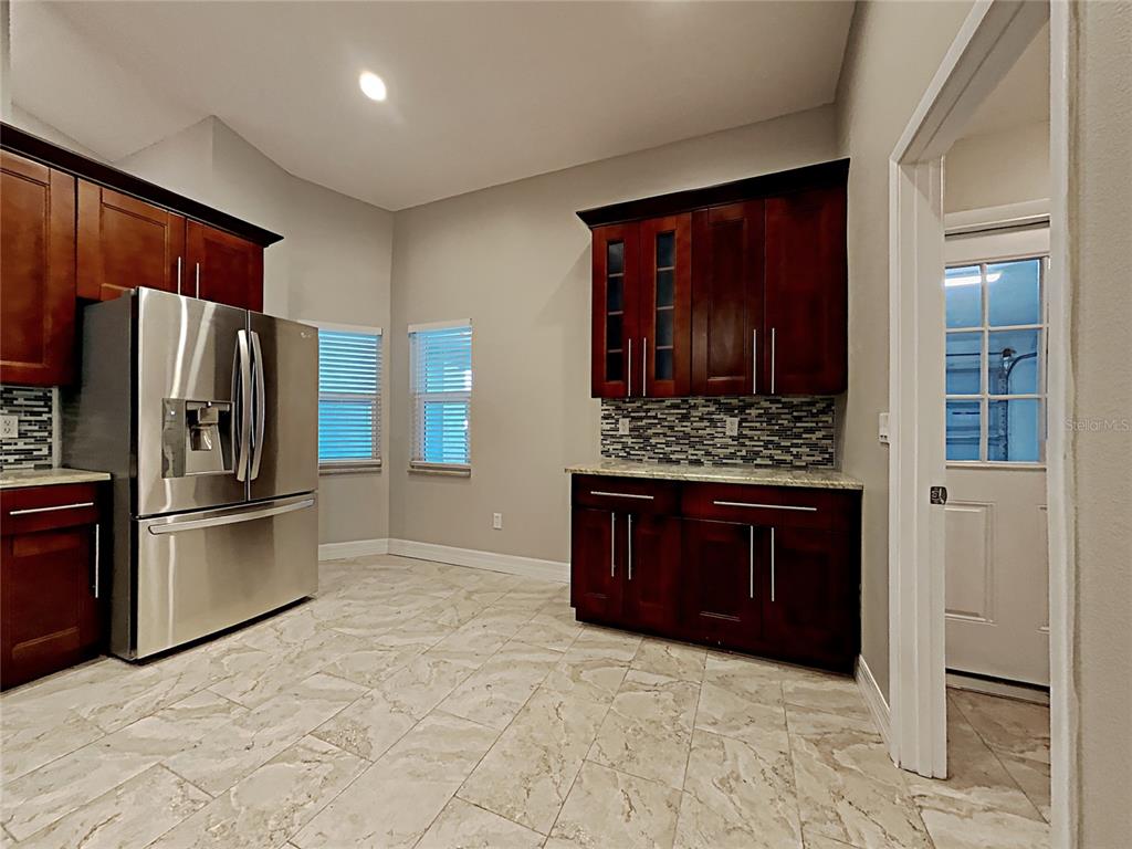 A kitchen features dark wood cabinets, stainless steel appliances, a tiled backsplash, and light flooring — 1237 BARMERE LANE, BRANDON, FL