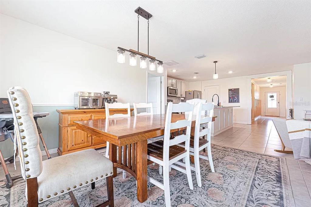 A dining area features a wooden table, white chairs, and a pendant light fixture — 8574 TRIUMPH CIRCLE, WILDWOOD, FL