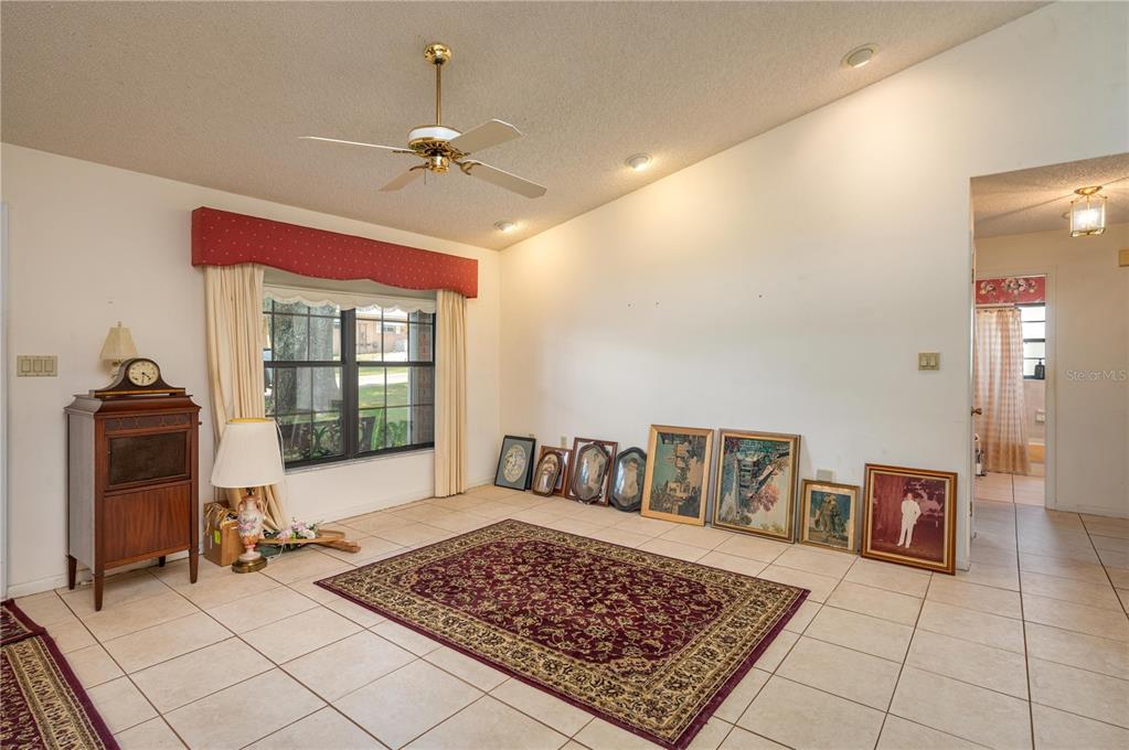 A living room with tile floors, a vaulted ceiling, a ceiling fan, and framed artwork — 113 EARLS COURT, SEBRING, FL