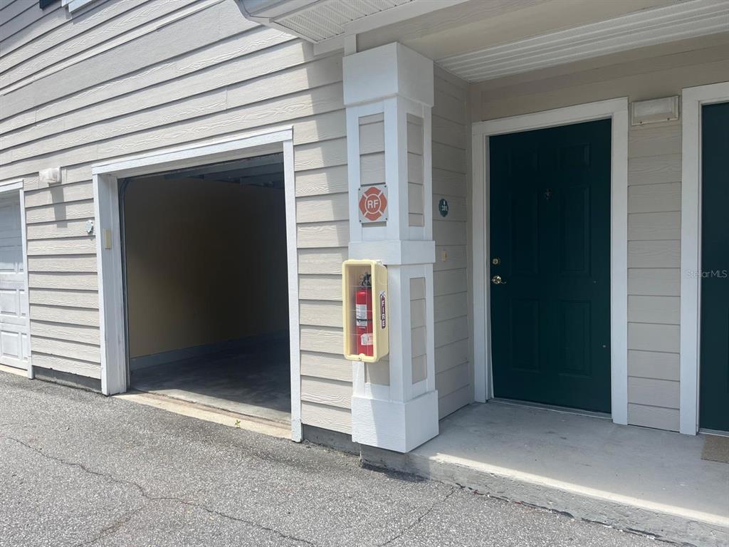 An exterior view of a garage entrance and a dark green front door with a fire extinguisher — 341 SOUTHERN PECAN CIRCLE UNIT 201, WINTER GARDEN, FL