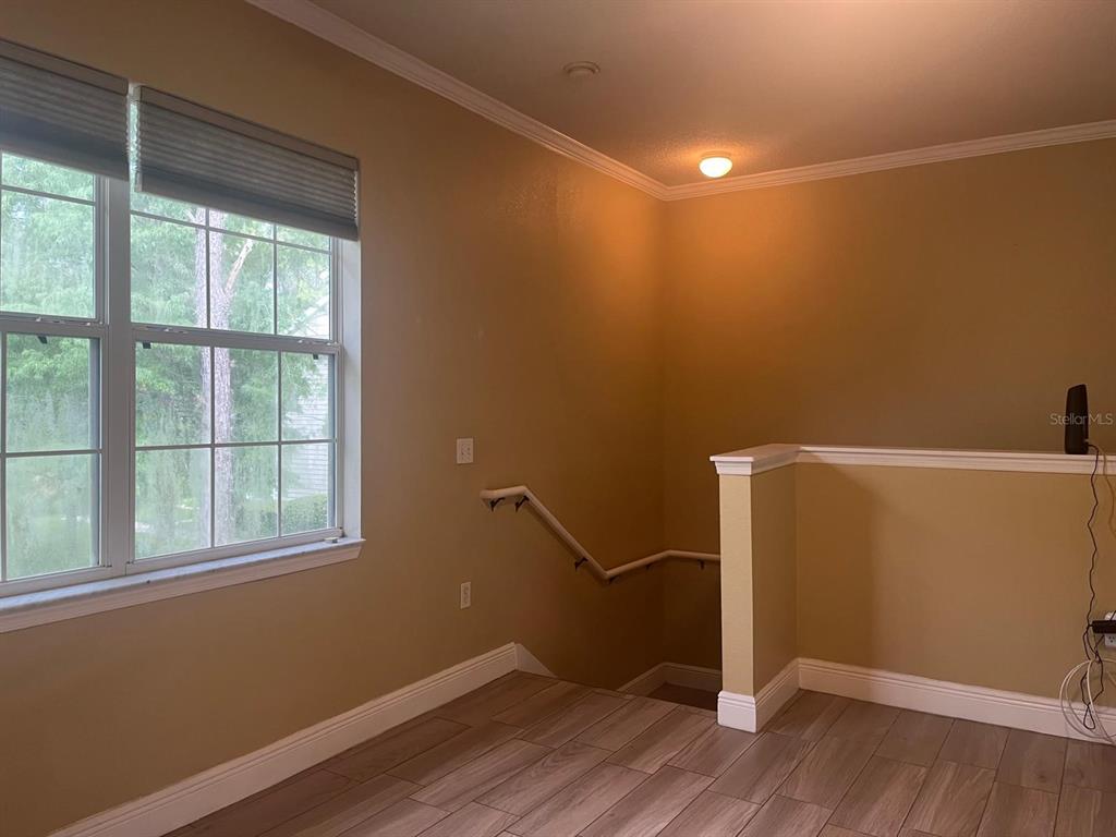 A landing with wood-look tile flooring leads to a staircase with a white handrail — 341 SOUTHERN PECAN CIRCLE UNIT 201, WINTER GARDEN, FL