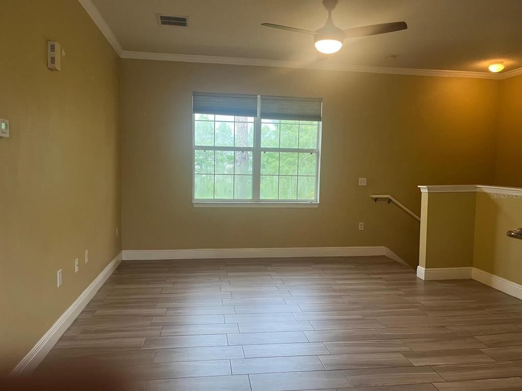 An empty room with light wood-look tile flooring, a ceiling fan, and a window — 341 SOUTHERN PECAN CIRCLE UNIT 201, WINTER GARDEN, FL