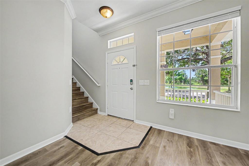 An entryway features wood-look flooring, a tiled landing, a staircase, and a front door — 5579 SOMERSBY ROAD, WINDERMERE, FL