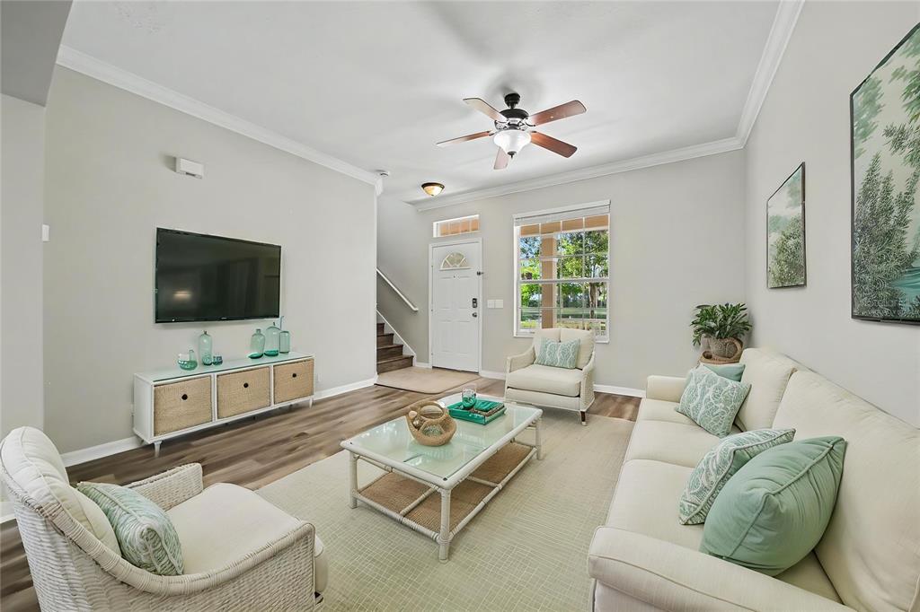 A living room features a white sofa, two armchairs, a glass coffee table, and flooring — 5579 SOMERSBY ROAD, WINDERMERE, FL