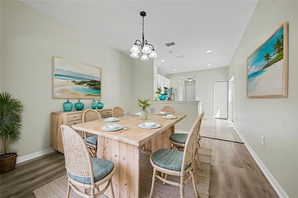 A dining room features a light wood table, wicker chairs, and coastal-themed wall art — 5579 SOMERSBY ROAD, WINDERMERE, FL