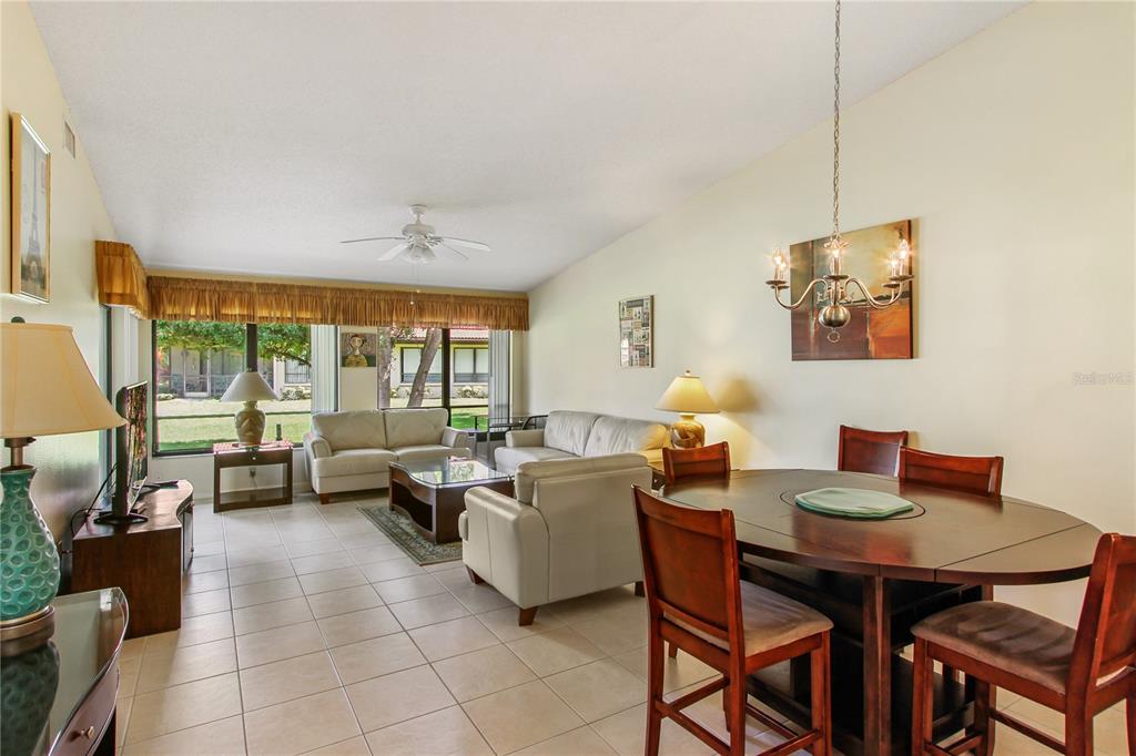 A living and dining room with tile floors, a ceiling fan, and large windows — 3715 PINECONE COURT UNIT 169, SARASOTA, FL