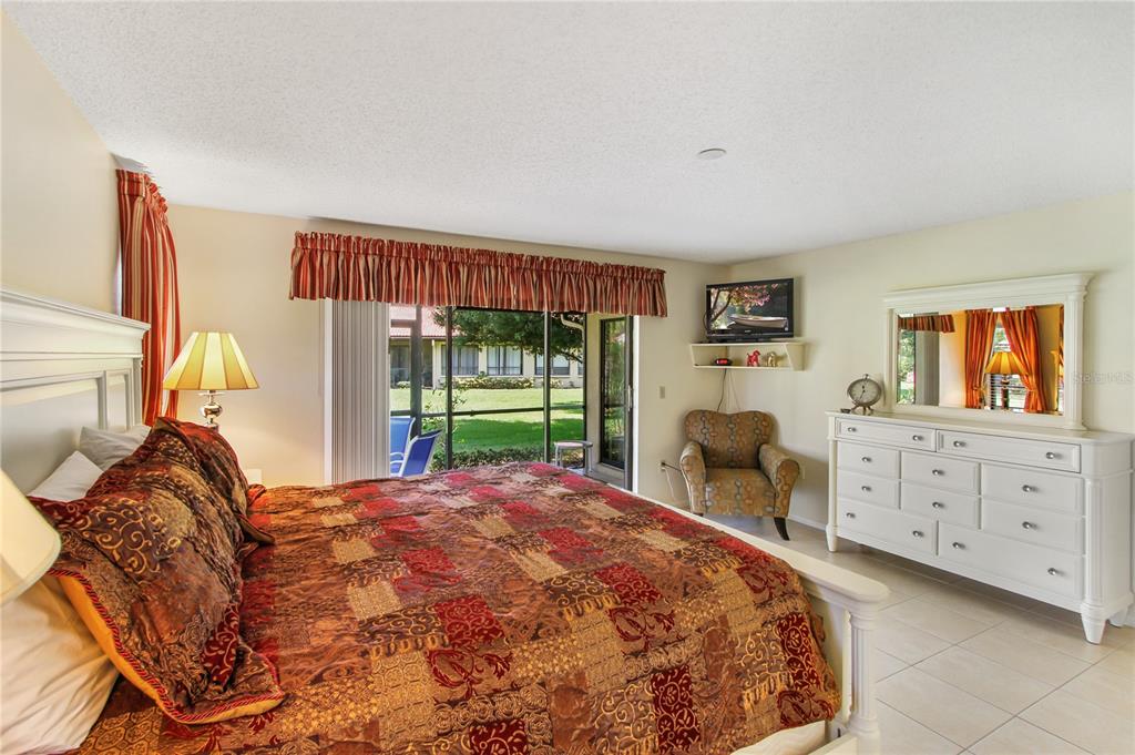A bedroom features a king bed with a patterned quilt, a white dresser, and sliding doors — 3715 PINECONE COURT UNIT 169, SARASOTA, FL