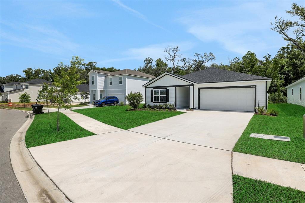 A single-story house with a white exterior, black trim, and a two-car garage — 3622 BELSTEAD WAY, ORANGE PARK, FL
