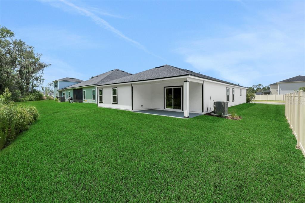 The exterior of a white single-story house features a covered patio and a grassy backyard — 3622 BELSTEAD WAY, ORANGE PARK, FL