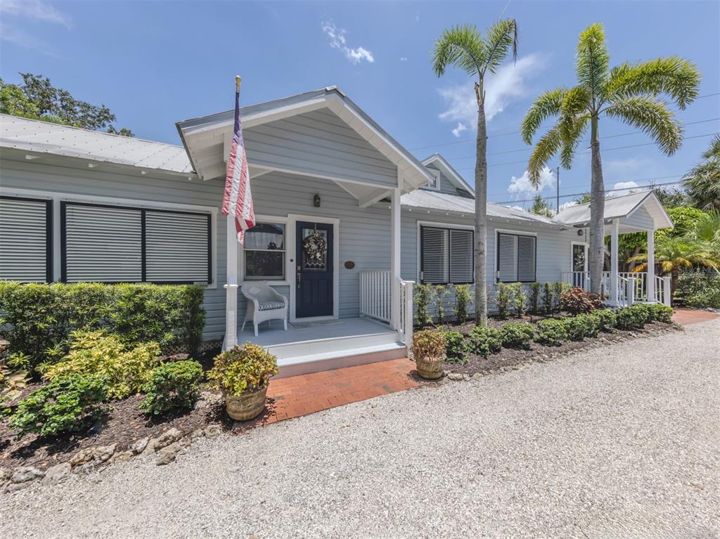A light blue house with a metal roof, a front porch, and palm trees — 726 EAGLE POINT DRIVE, VENICE, FL