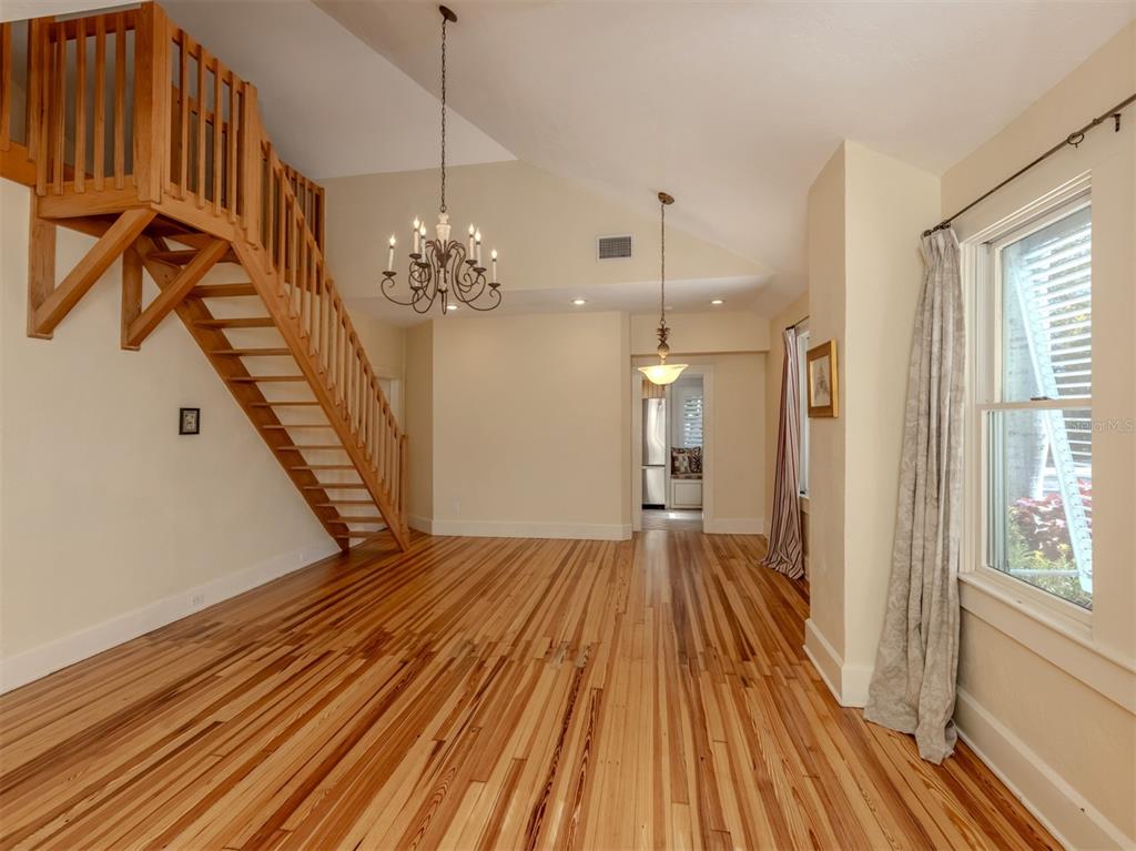 A living room features hardwood floors, a wooden staircase, and two hanging light fixtures — 726 EAGLE POINT DRIVE, VENICE, FL