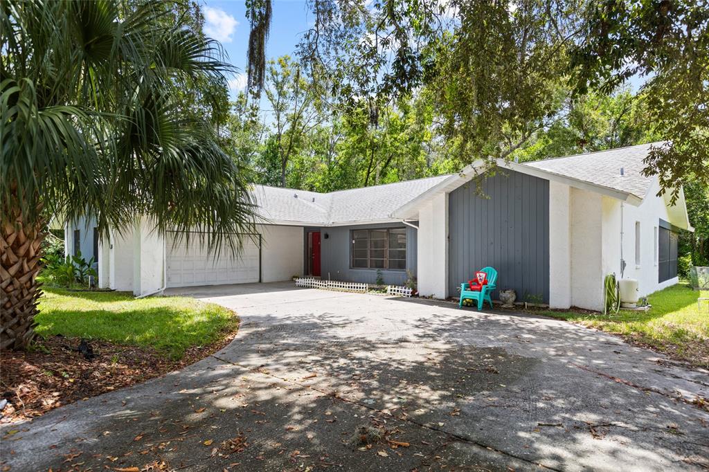 A single-story house with a white stucco exterior, gray vertical siding, and a concrete driveway — 19 HOLLYHOCK COURT, HOMOSASSA, FL