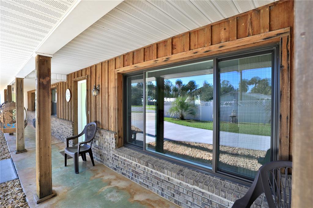 A single-story house with a light green garage door, wood siding, and a concrete driveway — 11230 SE TIMUCUAN ROAD, SUMMERFIELD, FL