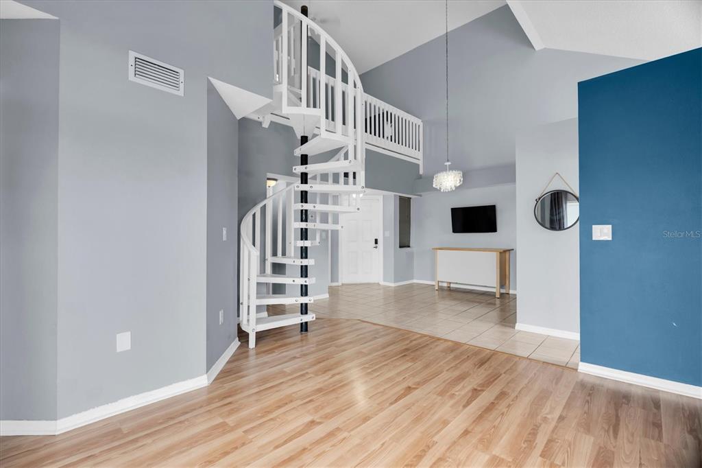 A living room features a blue sofa, a vaulted ceiling, and a grey media wall — 6931 STONES THROW CIRCLE N UNIT 5302, ST PETERSBURG, FL