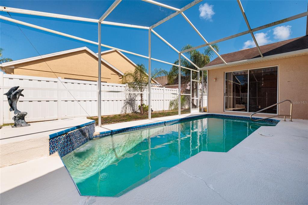A screened-in swimming pool with a small waterfall feature sits on a concrete patio — 1805 WOOD BEND STREET, TARPON SPRINGS, FL