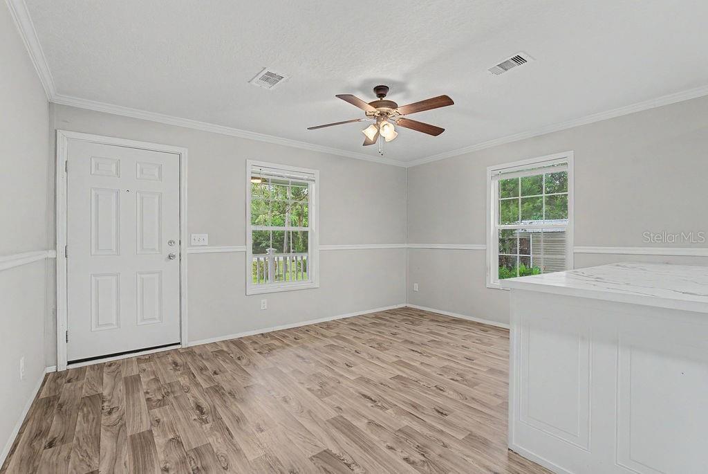 A room with light gray walls, wood-look flooring, a ceiling fan, and two windows — 641 MARSHBURN DRIVE, BRONSON, FL