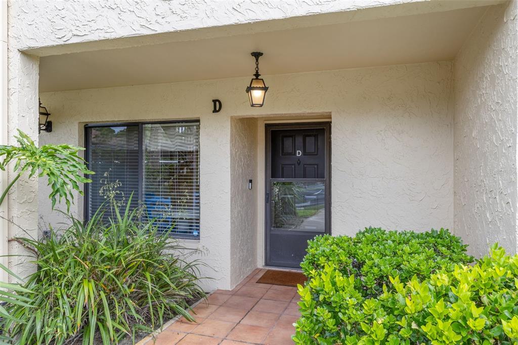 The exterior entrance of a residential unit features a dark door marked with the letter D — 1801 E LAKE ROAD UNIT 19D, PALM HARBOR, FL