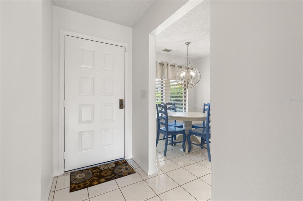 An entryway with a white door and tiled floor leads into a dining area — 1801 E LAKE ROAD UNIT 19D, PALM HARBOR, FL